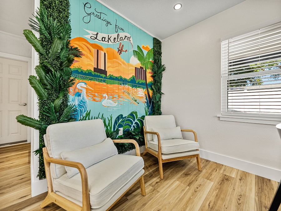 The modern dining area features sleek chairs and a minimalist table, perfect for comfort and connection. A striking mural by a local artist showcases Lakelands iconic lakes, landmarks, and downtown, adding a vibrant, personal touch.