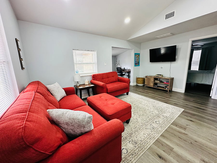 Welcome to this bright, open-concept living room and kitchen! Vaulted ceilings enhance the airy vibe, with natural light pouring in. Perfect for relaxing or sharing meals, this cozy space is designed for comfort and connection.