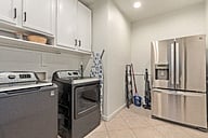 Large laundry room with large capacity washer and dryer, iron and ironing board,.