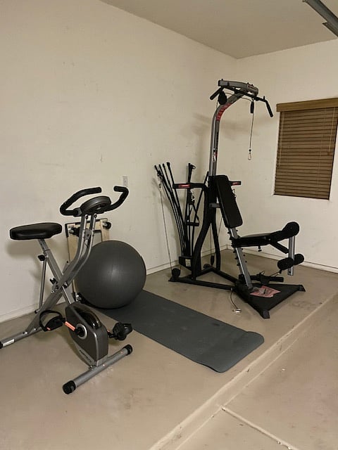 Work out equipment includes stationary bike, Bowflex machine and exercise ball.