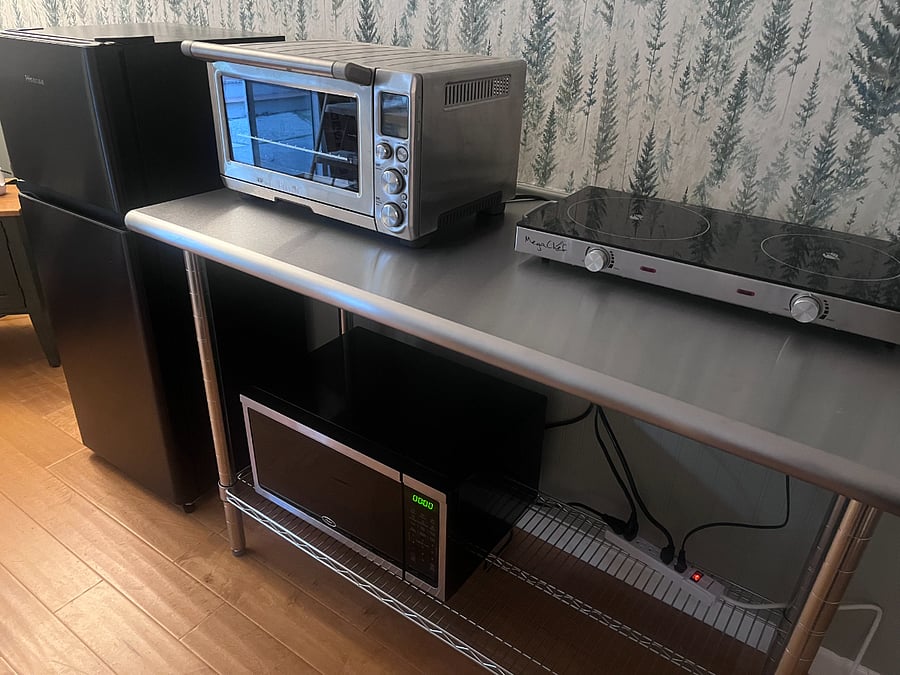 Countertop featuring electric stove, Breville toaster oven, and microwave. Stove can be easily moved to get more counter space.