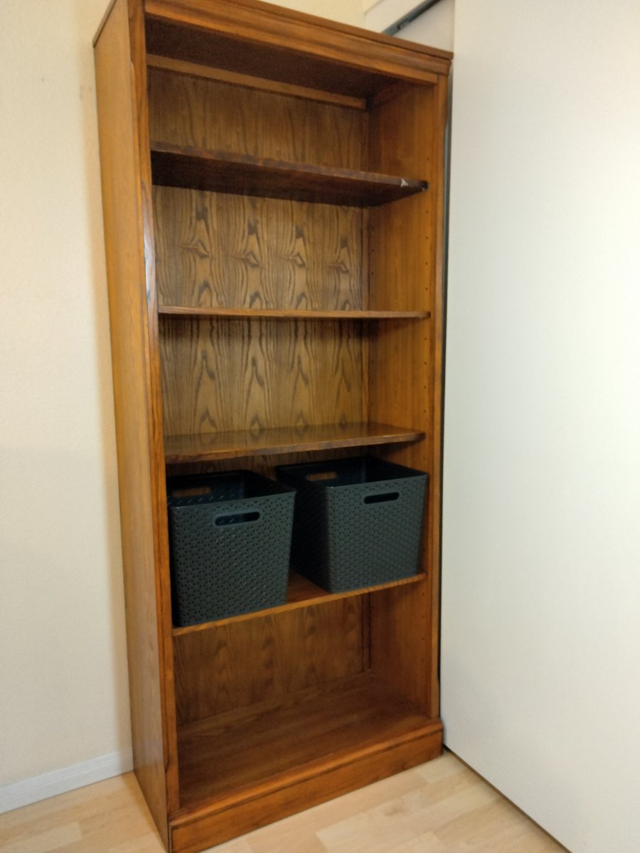 Tall bookshelf with storage/laundry bins.