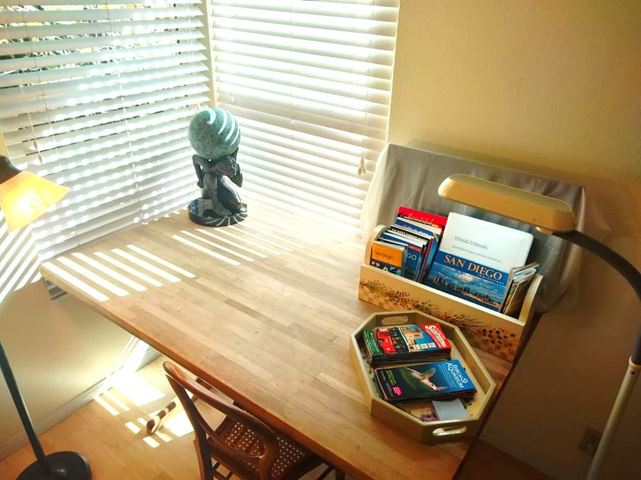 Large wooden table with plenty of natural light, and two lamps.