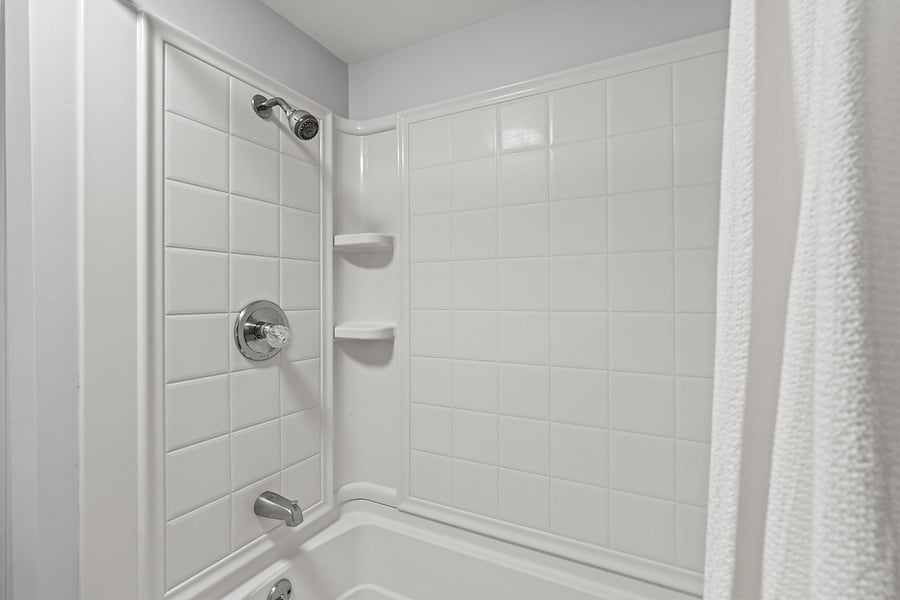 Bathroom in hallway with tub and shower, toilet, and sink near the primary bedroom