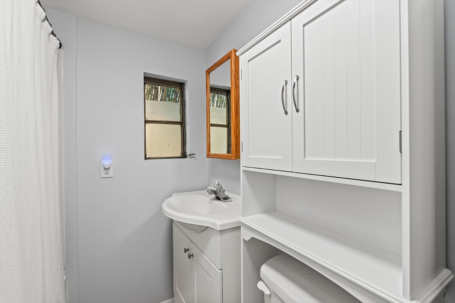 Bathroom in hallway with tub and shower, toilet, and sink near the primary bedroom