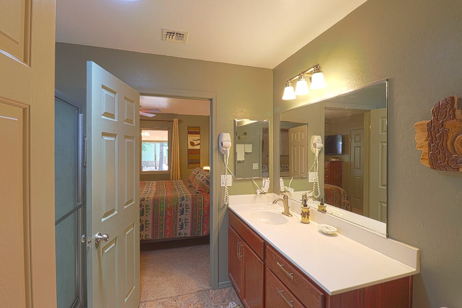 Large sink counter area and large mirror in the main bathroom. Both bathrooms have wall-mounted hair dryers.