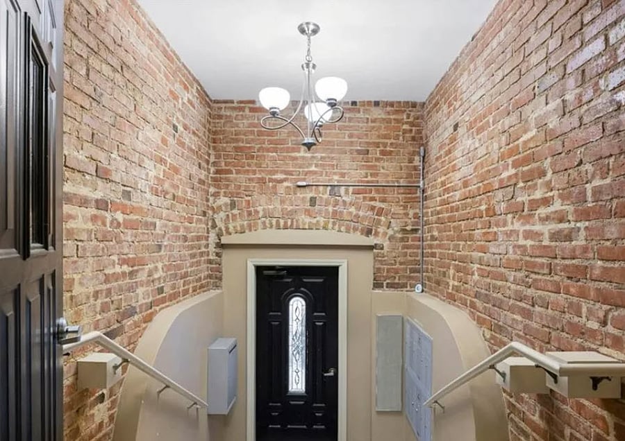 Secured access to building with exterior call box and mailbox in entryway.