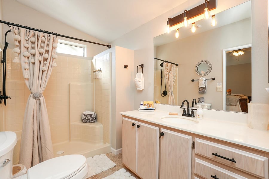 Primary ensuite bath with lots of shelving and shower has both rain head and wand. 