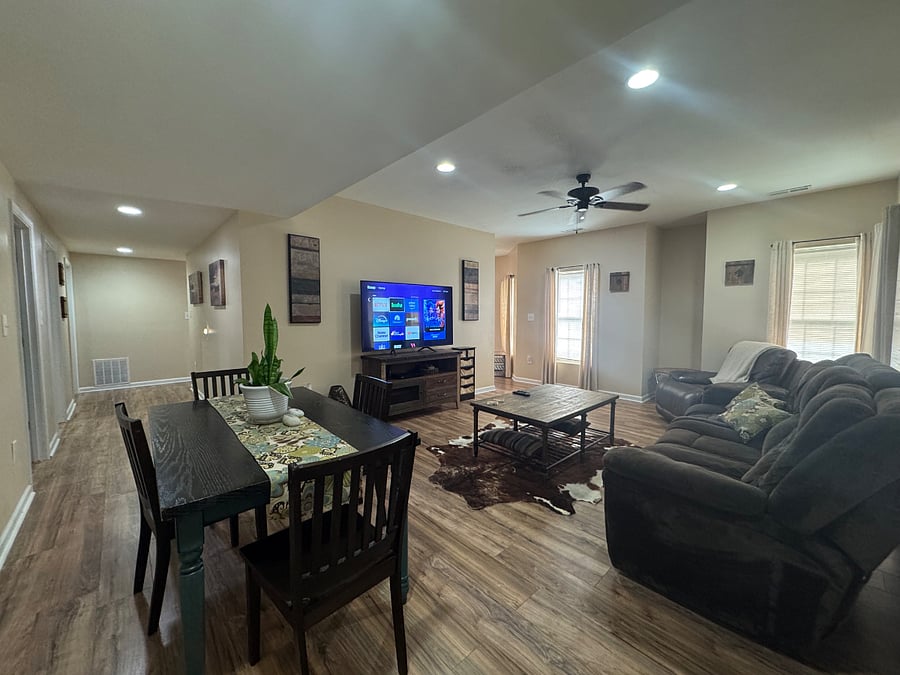 Living room and dining room combo (view 3); 3-person reclining couch, oversized reclining chair; additional view of wide left-side hallway to bedroom #1, bathroom and kitchen