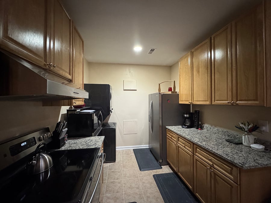 Kitchen (view 3); full size refrigerator and freezer, stacked washer/dryer with collapsible laundry basket for ease of storage on baker's rack shelf; step stool next to fridge, ample cabinets for food storage during long terms stays;
