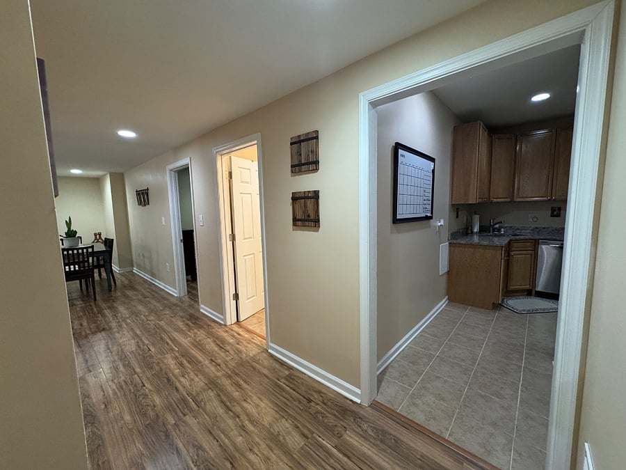 View leaving kitchen; extra-wide hallway leading toward bathroom, bedroom #1, and dining area/living room