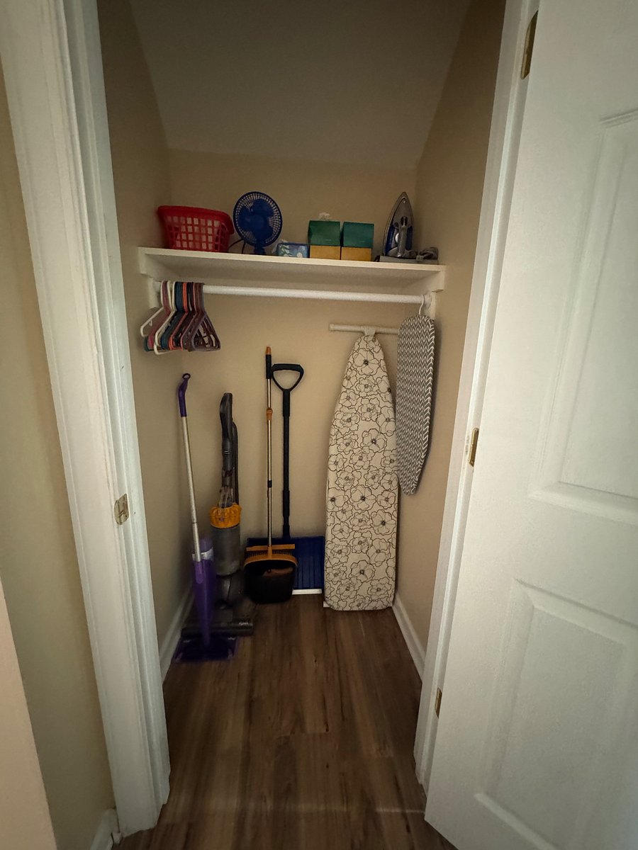 Coat Closet: Hallway between foyer and kitchen containing apartment essentials (e.g., Dyson vacuum, Swifter Wet Jet mop, broom/dust pan, ironing board/iron, snow shovel, small fan, first aid kit, and other starter essentials)