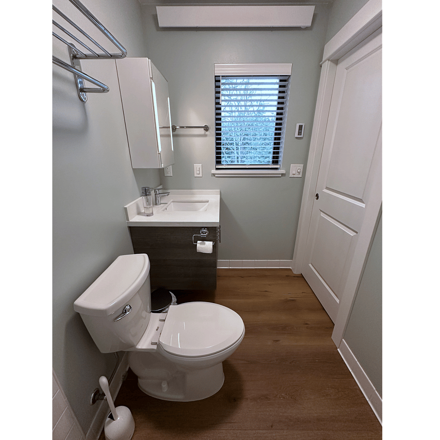 Tiled shower with cast-iron tub, rain head with hand sprayer, lighted mirror, and radiant cove heater.