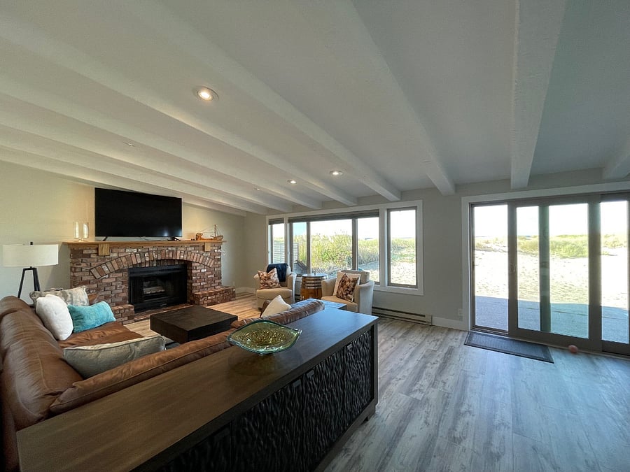 Expansive living with views to the back patio and ocean, ample seating, 70" smart TV, wood burning fireplace and adjacent office (photo take from living room entry). Expansive patio runs length of the house (photo take looking toward backside of house).