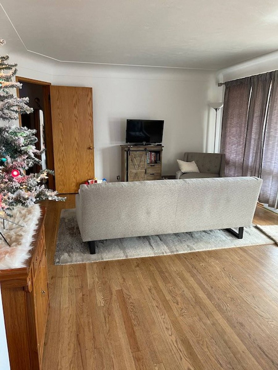 On the main floor, the front door opens to a spacious living room lite by an abundance of natural light. The living room is furnished with a modern yet comfortable sofa from Crate and Barrel, a television, stands and a table.