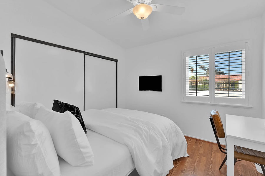 Bedroom 3 with queen bed, ceiling fan, window shutters, workspace, and smart TV