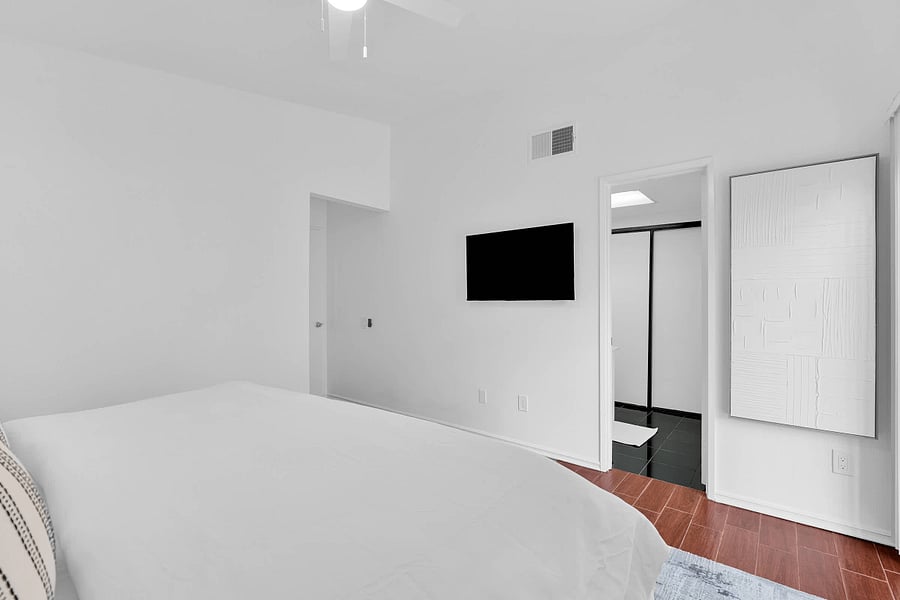Primary bedroom with king bed, ceiling fan, smart TV, and ensuite bathroom