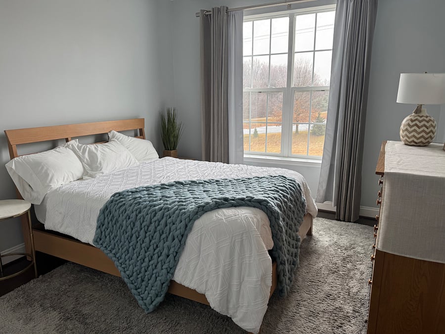 Fully furnished bedroom with a queen size bed and dresser that looks out to a beautiful pond. 