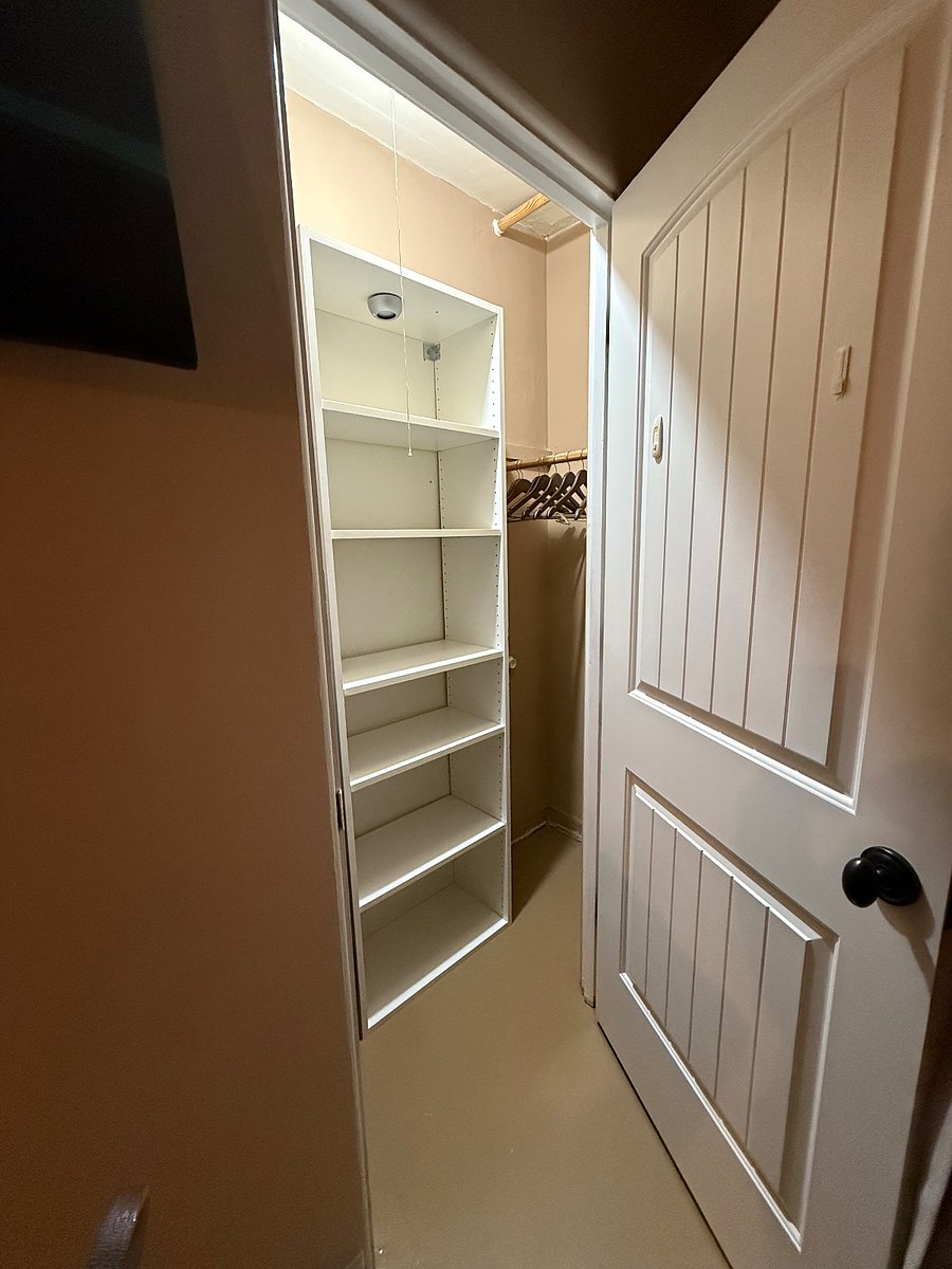 Primary bedroom closet with shelves. There is a large dresser in the bedroom for additional storage.