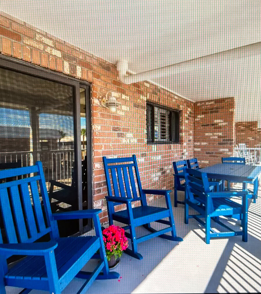 Large deck with partial view of ocean. View of swimming pool and community center below.