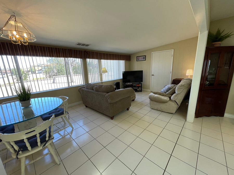 The family room includes one of two televisions in the house along with a round glass table for dining or games.