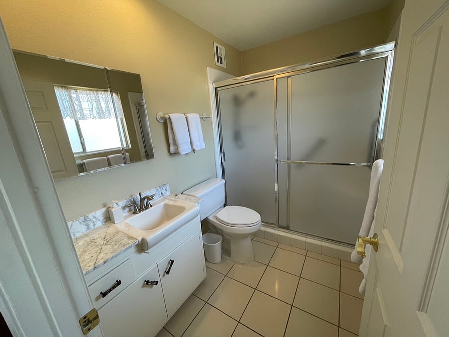 The primary bathroom features a walk-in shower with a seat. The vanity has a genuine marble countertop.
