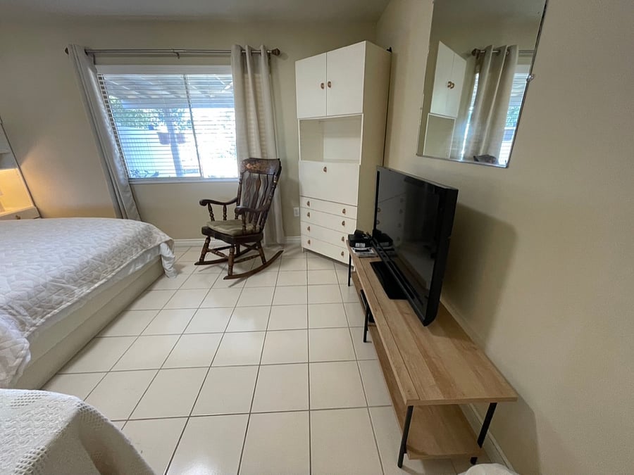 The guest bedroom features a second flat-screen television and a large closet with full-length mirrored doors.