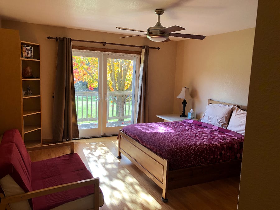 downstairs bedroom with queen bed and balcony