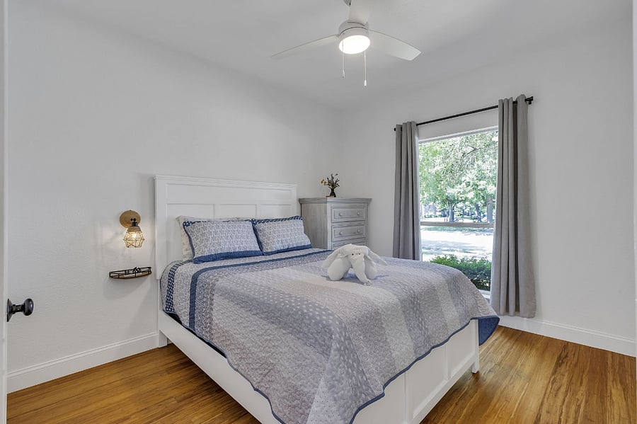 Queen bedroom with ceiling fan, side tables, dresser, and closet. Front view with black-out blinds.