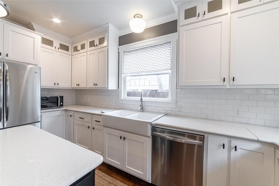 The farmhouse sink, subway tile backsplash, and glass-front ceiling-height cabinetry make dinner prep downright pleasant!