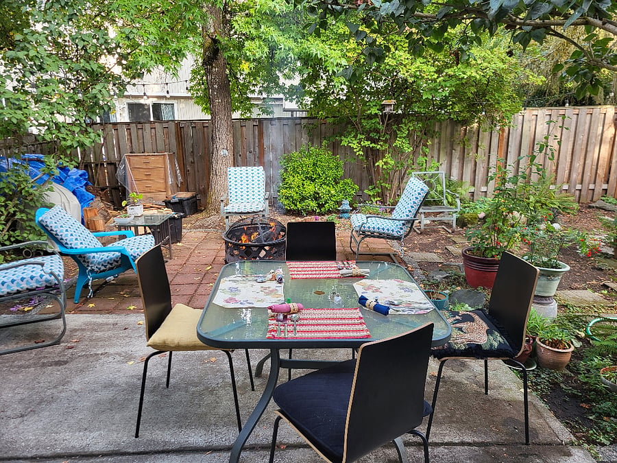 Portion of back yard with chairs and fire pit.