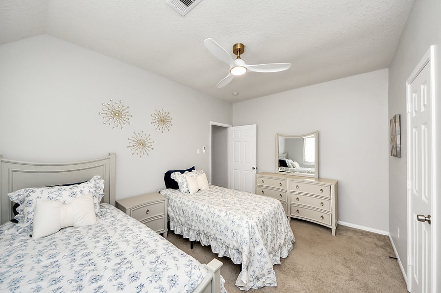 Guest bedroom with 2 twin beds, dresser, ceiling fan and closet space.
