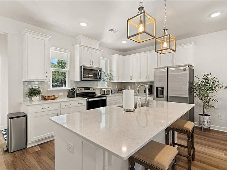 The open modern kitchen seamlessly flows into the main living area, offering an airy and connected feel. Sleek cabinetry, high-end appliances, and elegant stone countertops provide both style and functionality. A large island with bar seating invites casual gatherings, while expansive windows frame breathtaking marsh views, bringing natures beauty indoors. Thoughtfully designed lighting and a neutral coastal palette enhance the kitchens sophisticated yet inviting atmosphere, making it a perfect space for cooking, entertaining, and enjoying the serene surroundings.