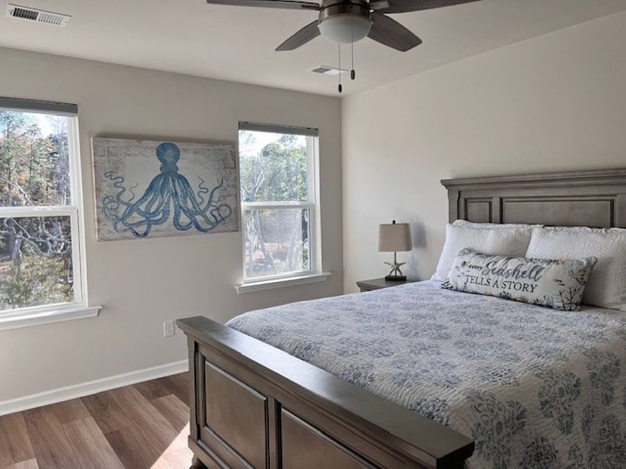 The primary bedroom is a serene retreat, offering breathtaking views of the marsh and tidal creek. Wake up to the beauty of nature through expansive windows that fill the space with natural light. Designed for ultimate comfort, this elegant sanctuary features a plush bed, stylish furnishings, and a calming coastal palette and a generous walk-in closet. The luxurious ensuite bath boasts a spacious walk-in shower and double vanity sinks, providing the perfect private escape to relax and recharge.