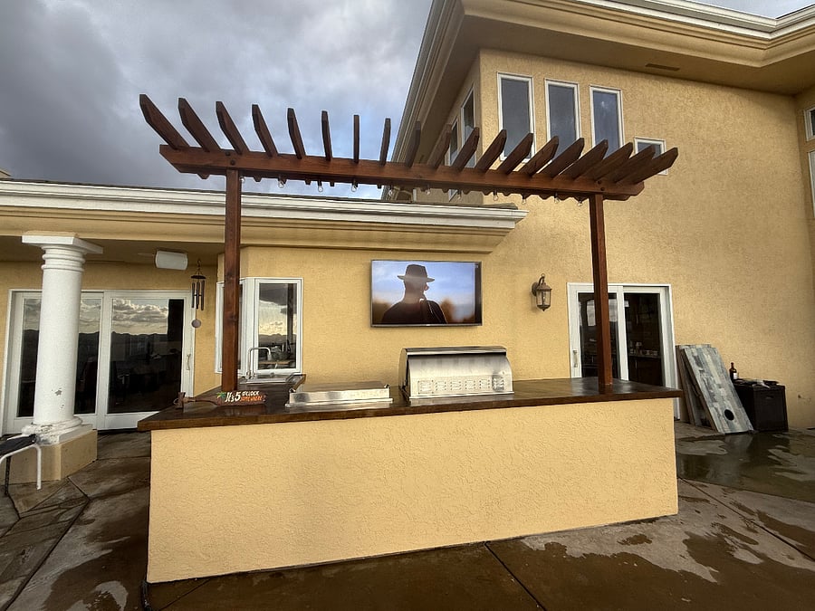 Outdoor kitchen with grill, griddle, refrigerator, and tv