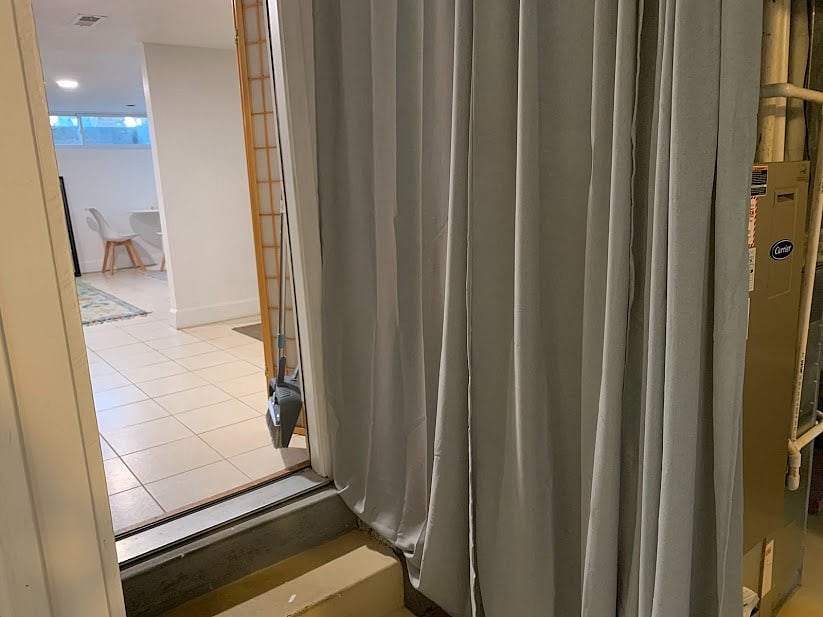 Hallway to the living area from the bedroom. HVAC equipment is behind the curtains.