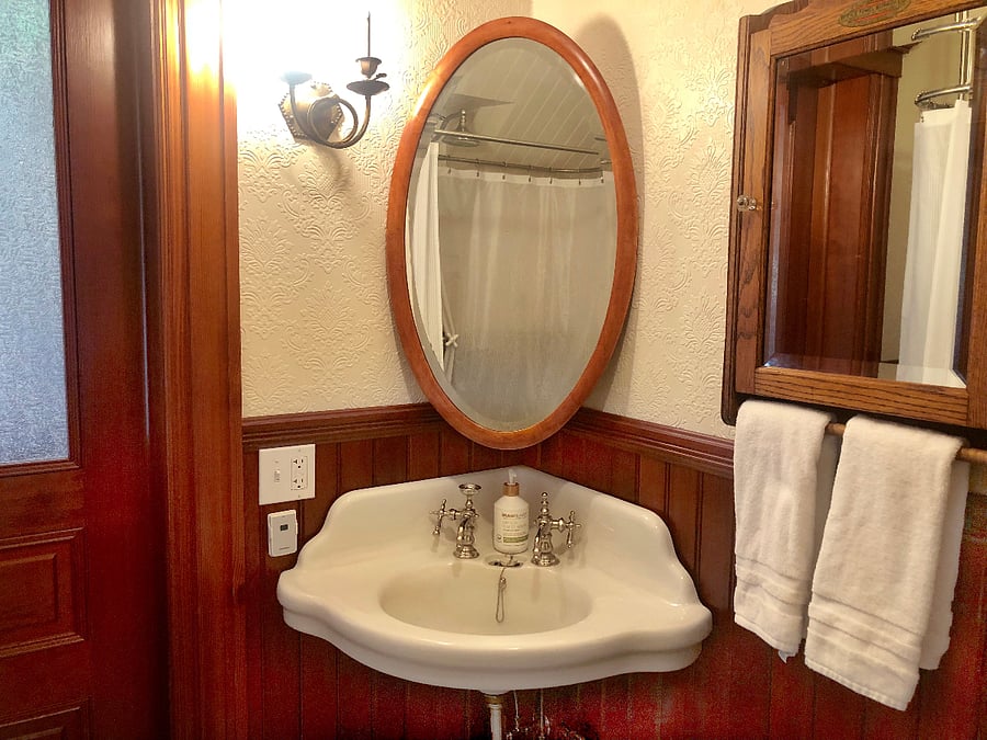 Enjoy the elegant corner serpentine sink with large oval beveled mirror and plush hand towels, right at your fingertips.