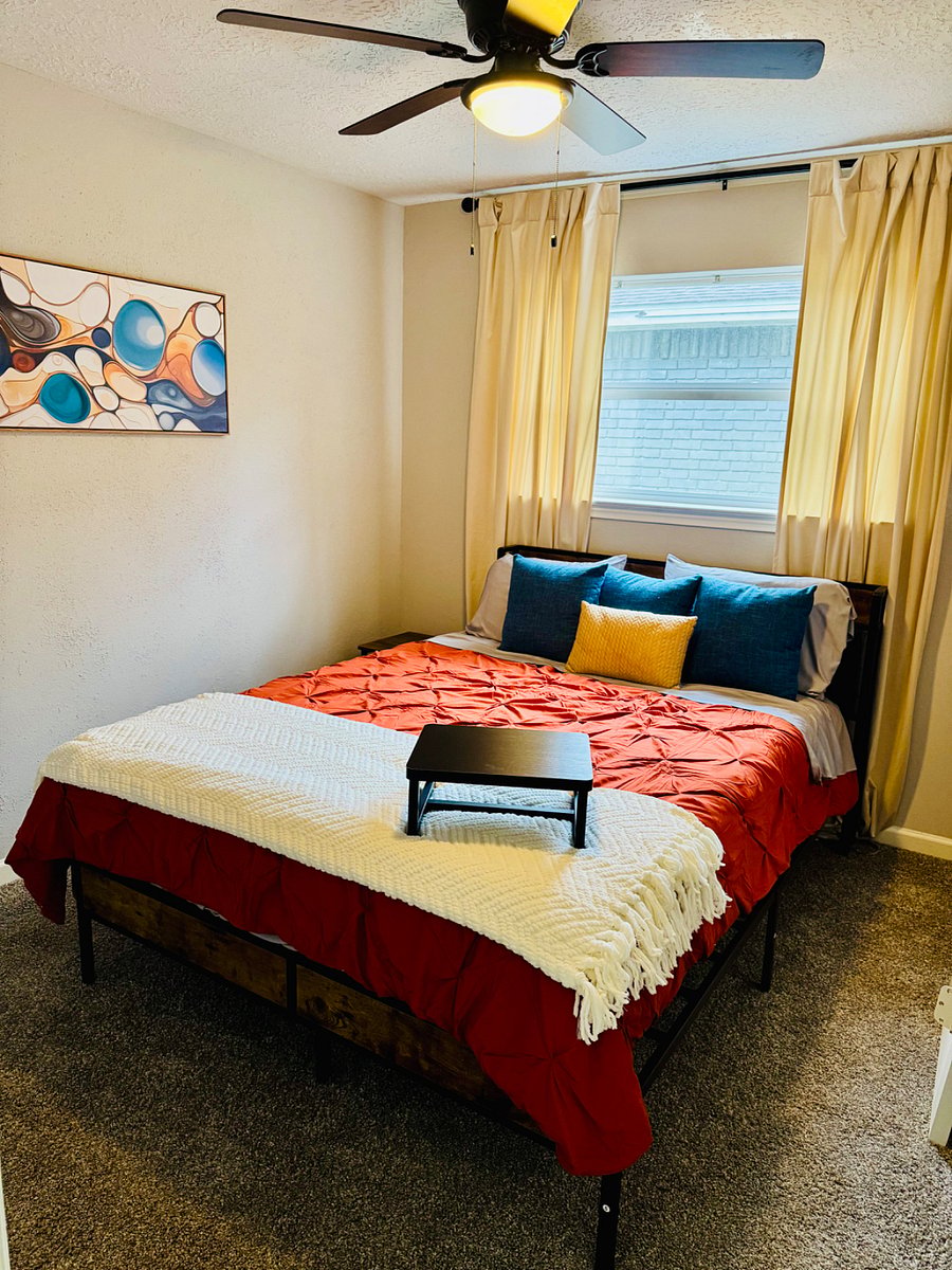 Middle bedroom with queen bed, smart tv, closet, and a small dresser. 