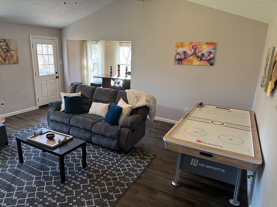 Living room with comfy couch, 75 tv (not pictured) and an air hockey table. 