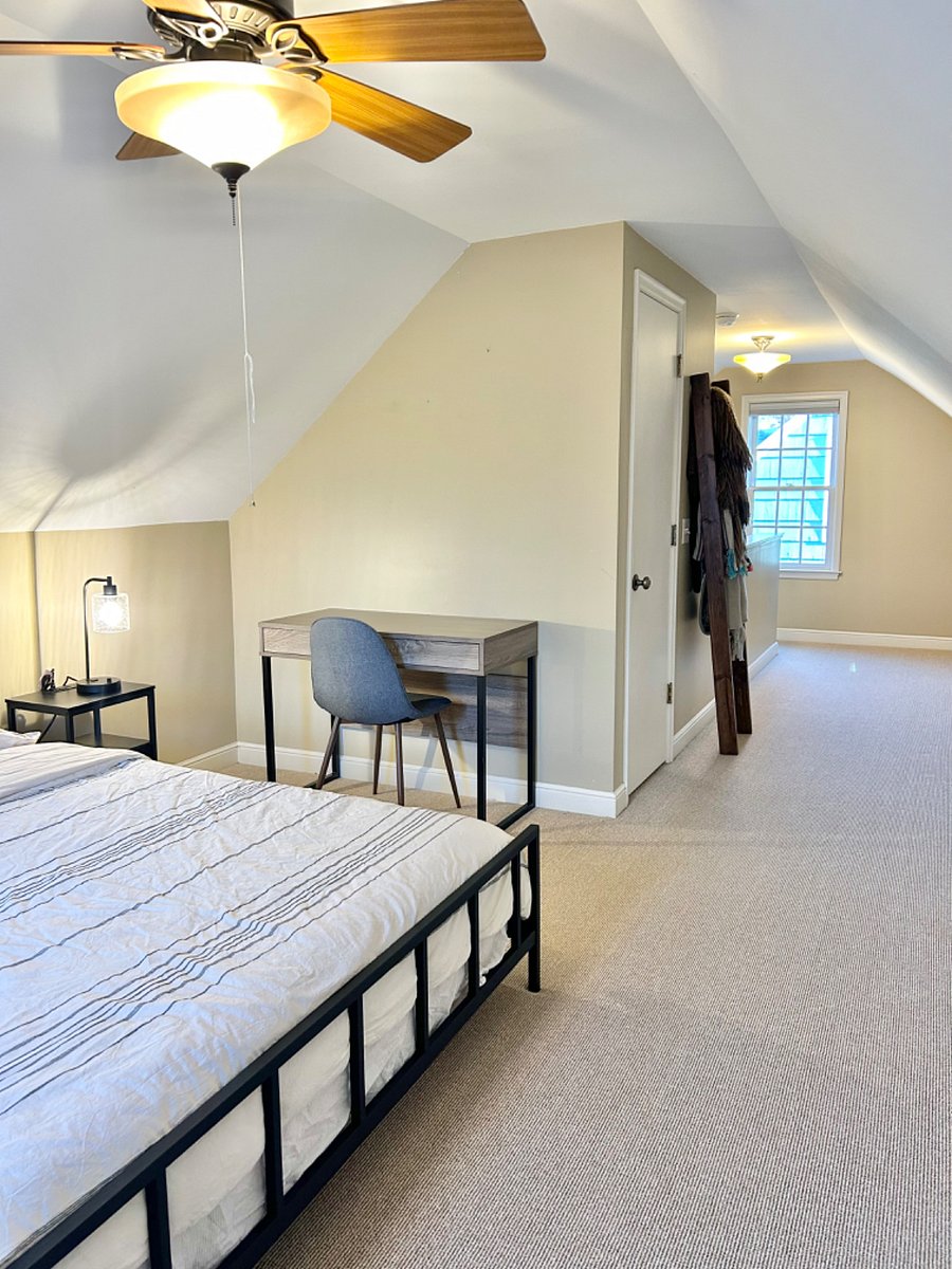 Upstairs bedroom featuring a king sized bed, dresser, walk-in closet and desk area.