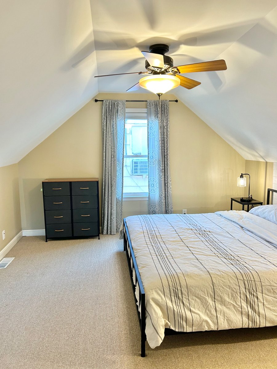Upstairs bedroom featuring a king sized bed, dresser, walk-in closet and desk area.