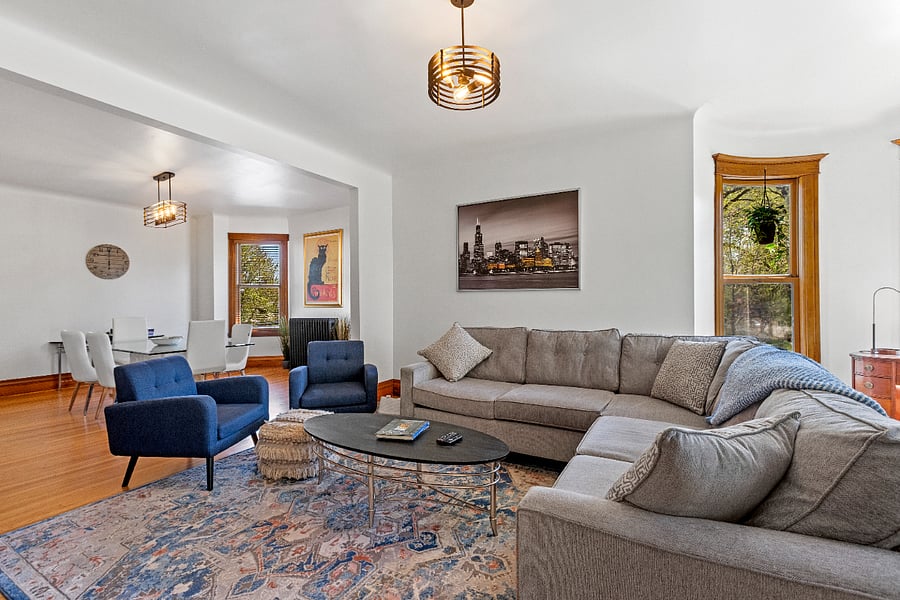 This spacious living room offers ample seating for both lively gatherings or a peaceful, much-needed nap. Enjoy entertainment with a Smart TV, DVD player, an array of DVDs, and a thoughtfully curated library of books. Lush plants bring a touch of nature indoors, while an antique heirloom kidney-shaped desk creates a charming workstation in the turret, tucked elegantly in the corner.