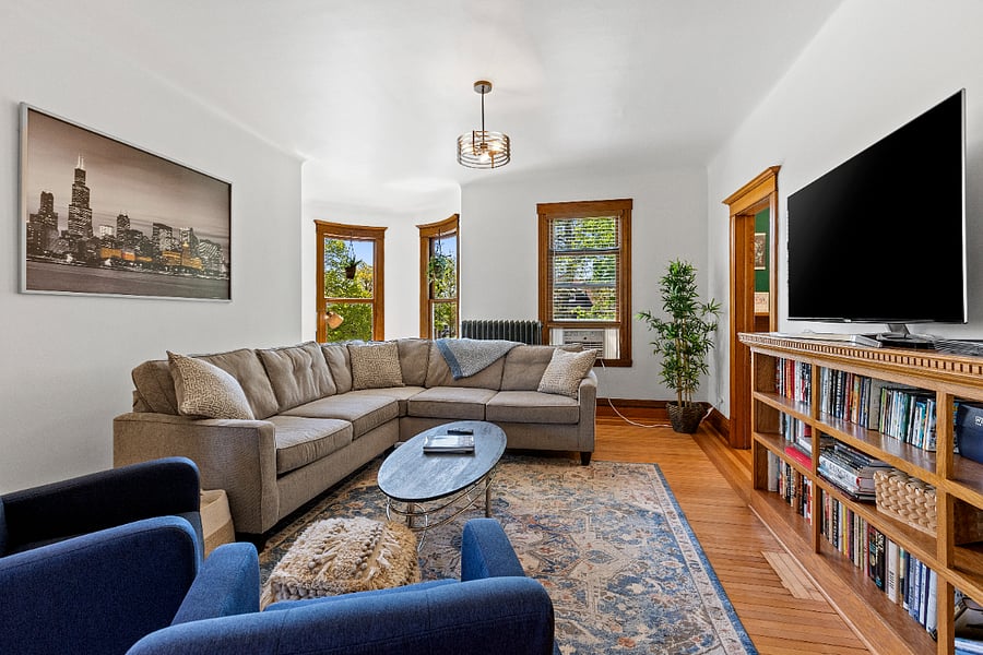 This spacious living room offers ample seating for both lively gatherings or a peaceful, much-needed nap. Enjoy entertainment with a Smart TV, DVD player, an array of DVDs, and a thoughtfully curated library of books. Lush plants bring a touch of nature indoors, while an antique heirloom kidney-shaped desk creates a charming workstation in the turret, tucked elegantly in the corner.