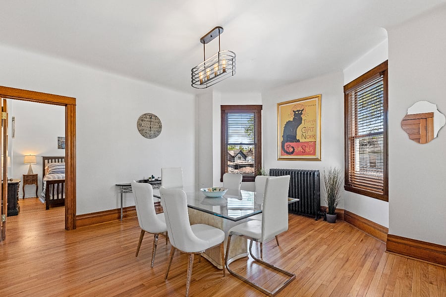 Step into a bright and airy formal dining room, where natural light pours in to highlight the elegant white leather and glass dining set. Thoughtfully curated artwork and lush greenery add a touch of sophistication and warmth, creating the perfect setting for memorable meals and gatherings.