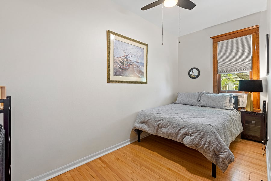 Bedroom two features a comfortable queen bed with views of the serene side lot, creating a peaceful retreat. It is equipped with room-darkening blinds, a ceiling fan, and an AC unit for optimal comfort. A spacious closet provides plenty of storage for your belongings.