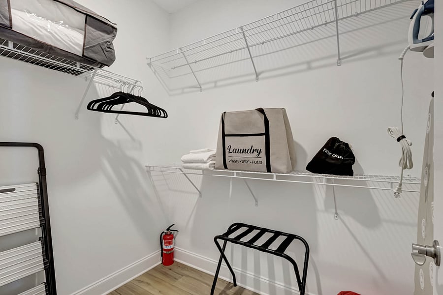 Primary Closet with Iron and Ironing Board along with step stool extra pillows and hangers