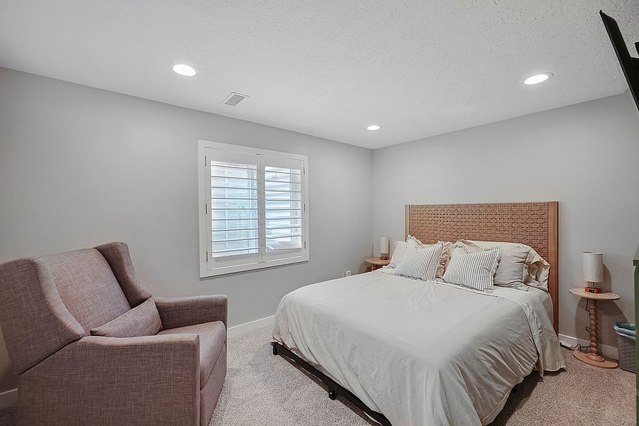 Bedroom # 3 Queen bed, smart TV, Dresser and large closet. Extra blankets, fan, heater, hangers, dresser, book shelf space. Recliner rocker. Dimmable lamps with charging station. Plantation shutters on a very large South facing window. Let light in when you want-and not feel like you are living in a basement-or shut the shutters for darkness. Very large window well that is equipped with a ladder for emergency exit if needed. Grate on top for security.