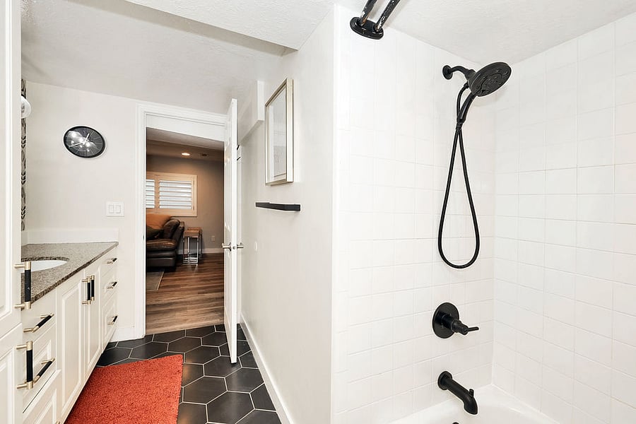 Large bathroom with deep tub with shower. Bath, hand, face towels, floor mats provided.