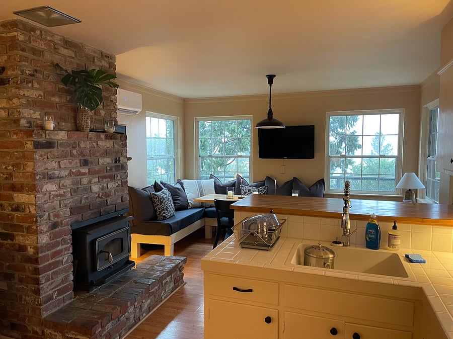 Cozy kitchen with wood burning stove (or a mini-split is available for heat/AC).  Corner couch seating area with views of the hills and adjustable TV. 
