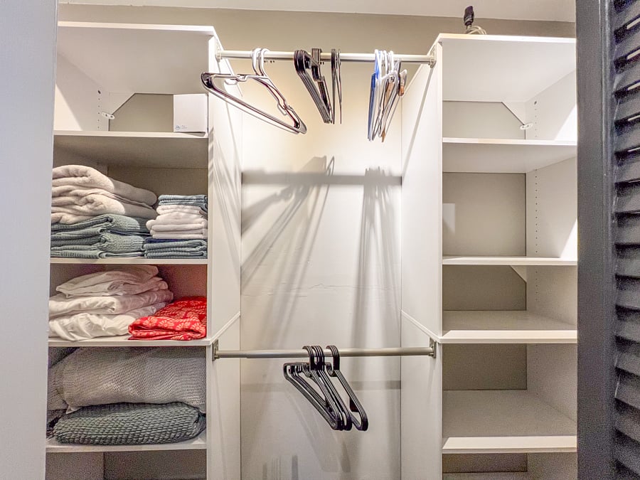 Closet in the bedroom with ample space, spare bed linens, towels, washcloths and hangers.